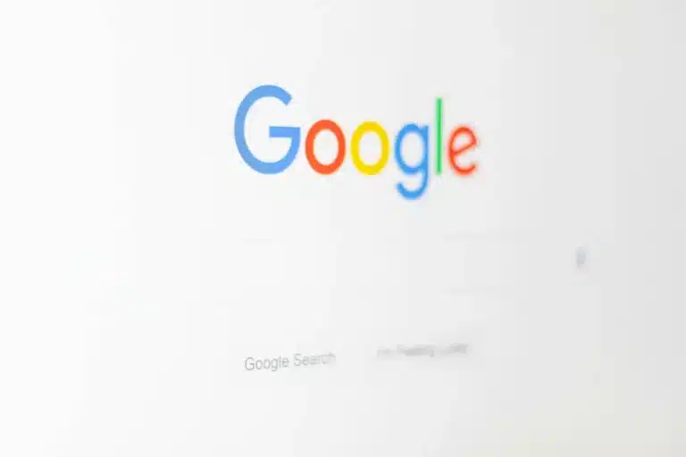 Google logo in multicolored letters on a white background with a faint search bar below.