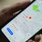 Hand holding a smartphone showing Google Maps with red location pins around a butcher shop.