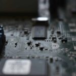 Close-up of a computer motherboard showing a central socket, blue terminal blocks on the left, and many tiny surface-mount components.