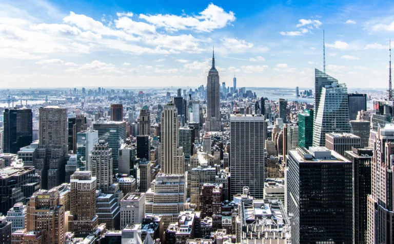 Manhattan skyline centered on the Empire State Building, with surrounding skyscrapers under a blue sky.